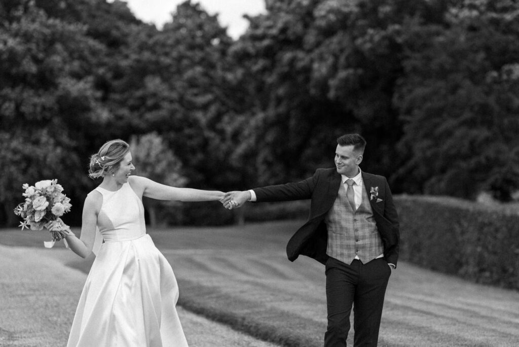 Bride and groom holding hands and laughing together at Bruisyard Hall