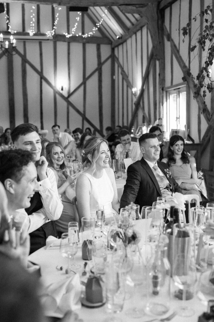 Bride and groom smiling and reacting emotionally during the wedding speeches at Bruisyard Hall