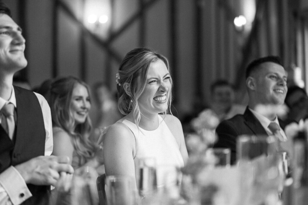 Bride smiling and reacting emotionally during the wedding speeches at Bruisyard Hall