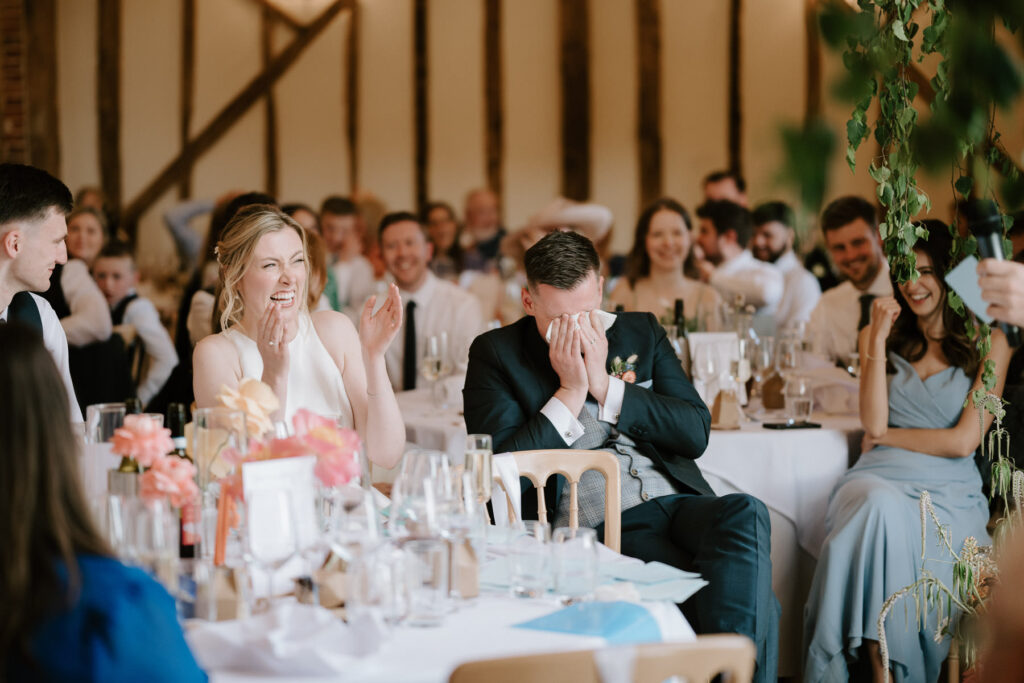 Guests clapping and smiling during the wedding speeches at Bruisyard Hall