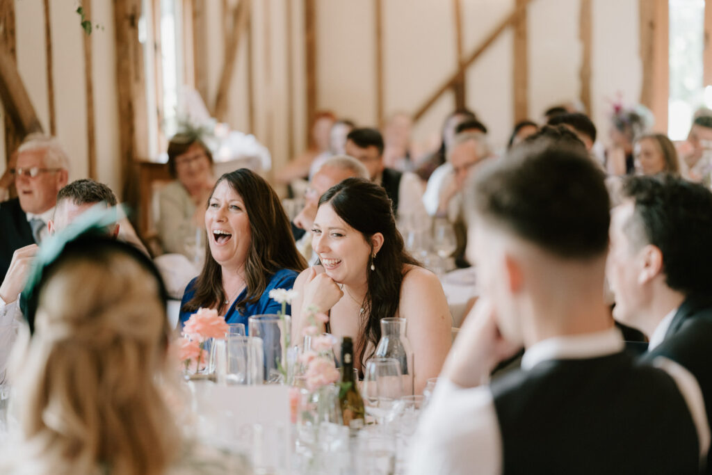 Wedding guests laughing and reacting during speeches at Bruisyard Hall