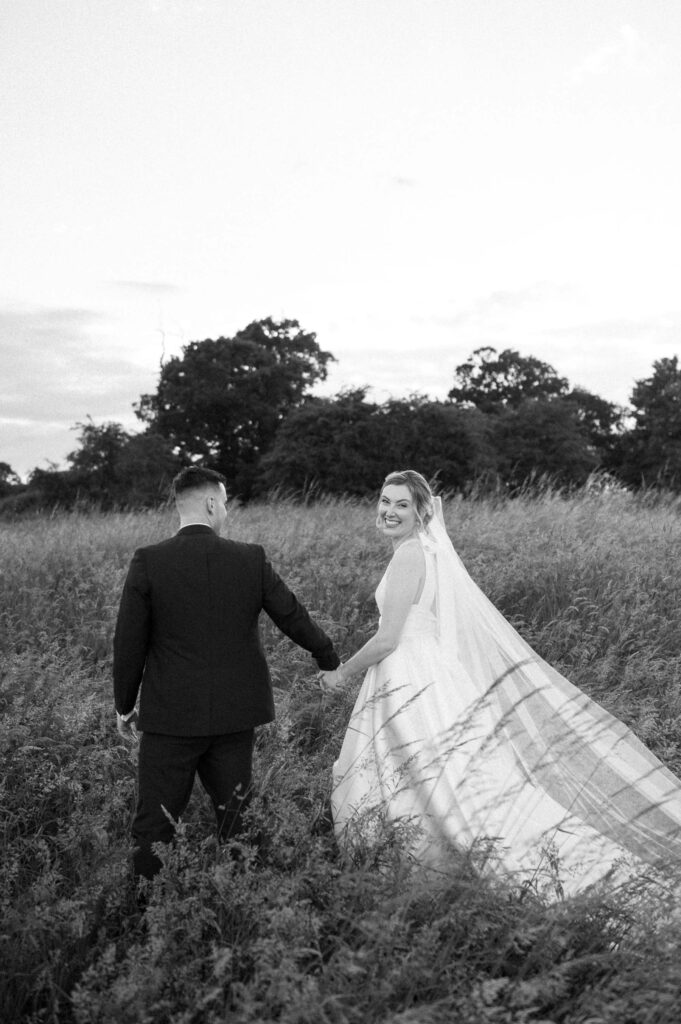 bride and groom walking off in field at bruisyard hall