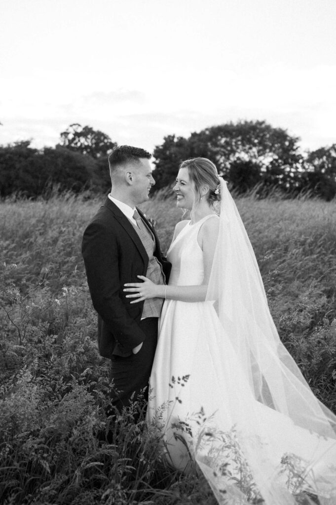 bride and groom smiling and talking in field 