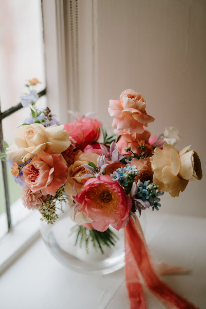 Close-up of bride's colourful summer wedding bouquet by the window at Bruisyard Hall