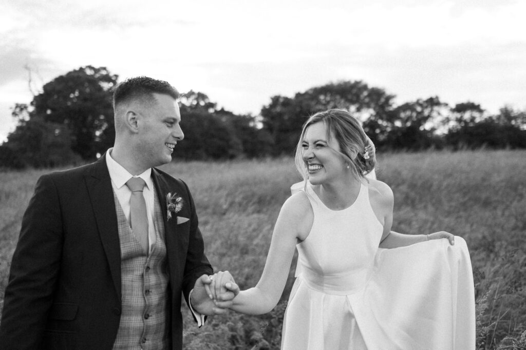 bride and groom walking hand in hand smiling at bruisyard hall