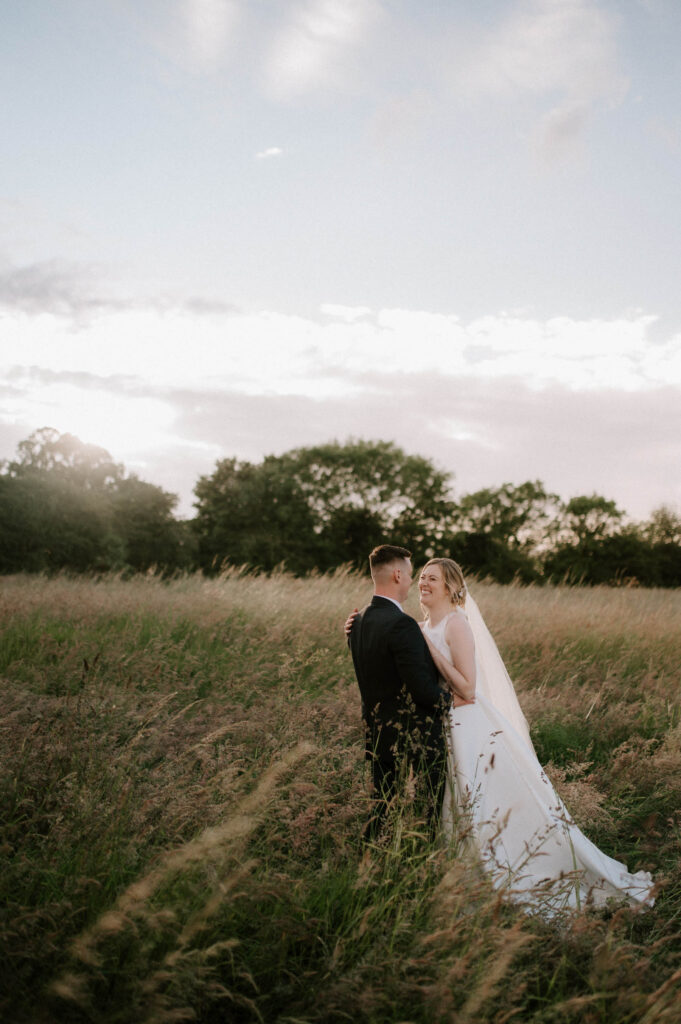 bride and groom sharing a moment in field at sunset at bruisyard hall