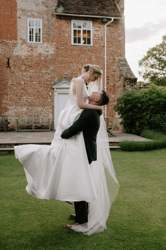 groom lifting bride in gardens at bruisyard hall