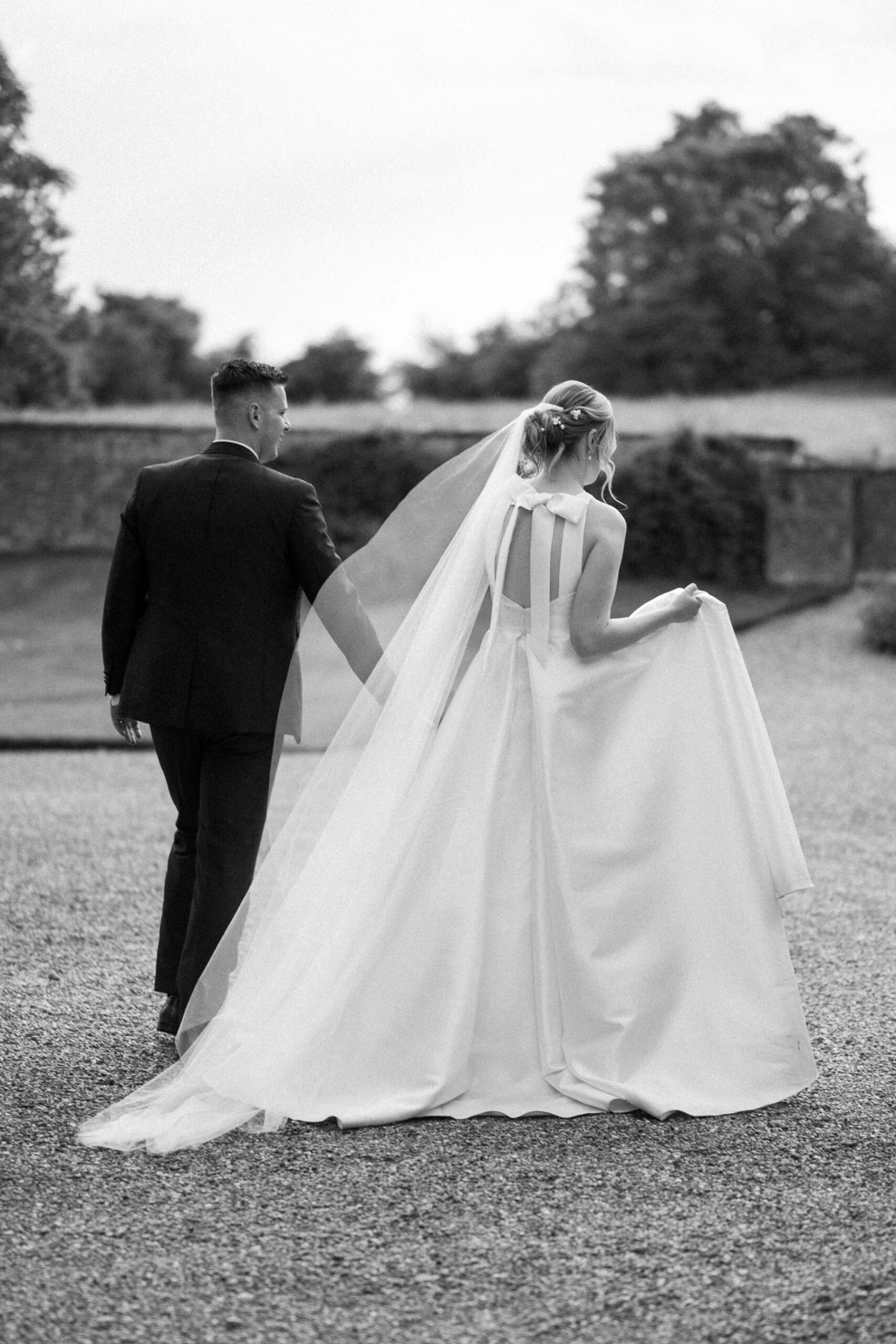Bride and groom walking hand in hand away from the camera at Bruisyard Hall