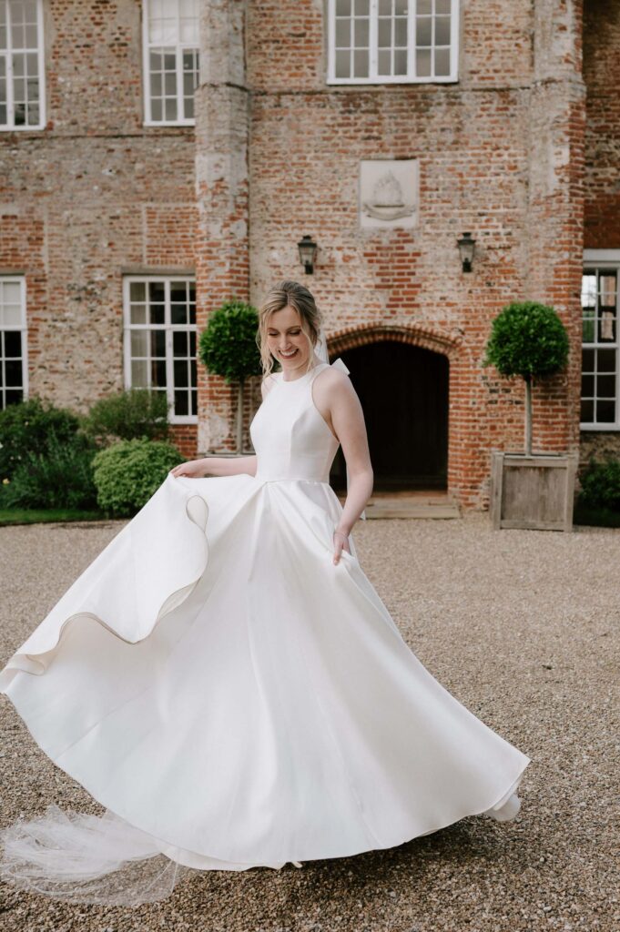Bride walking away with the groom while holding her dress at Bruisyard Hall