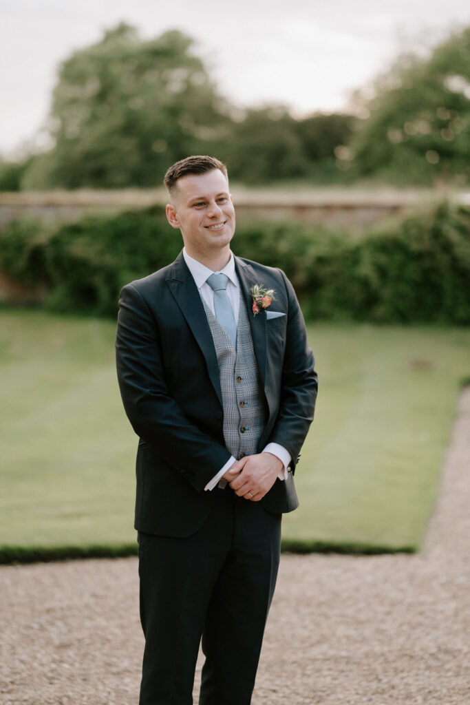 groom standing smiling at bride