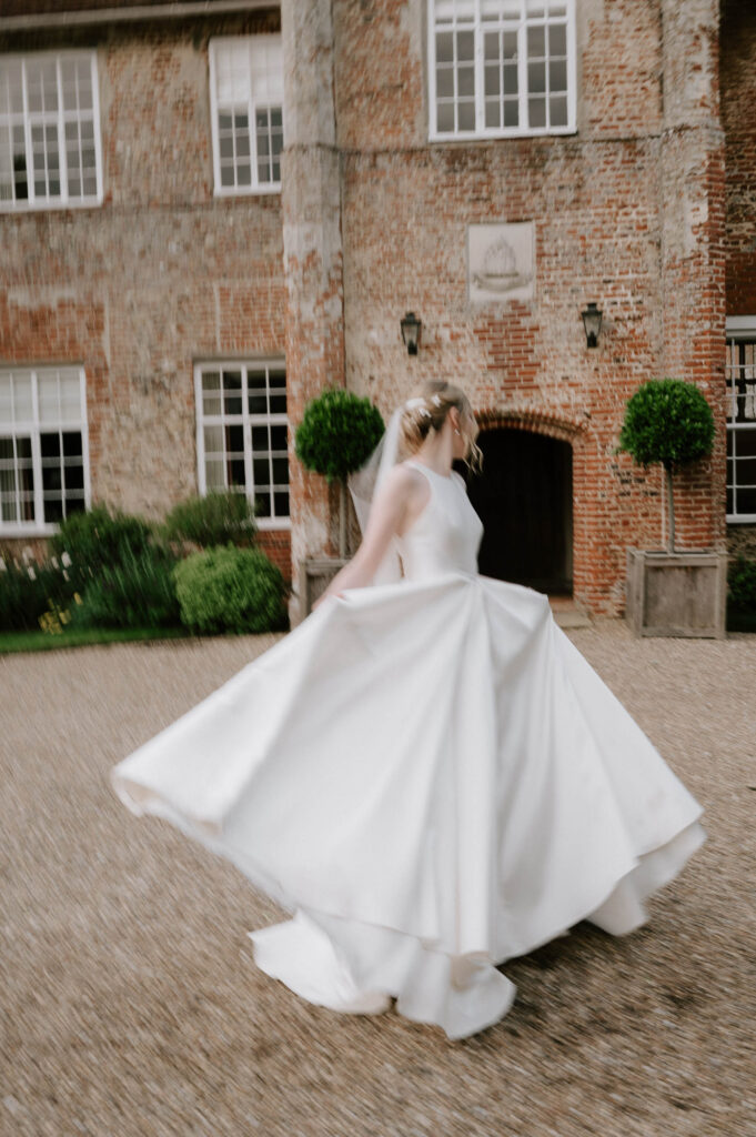 Bride lifting her dress while standing with the groom at Bruisyard Hall