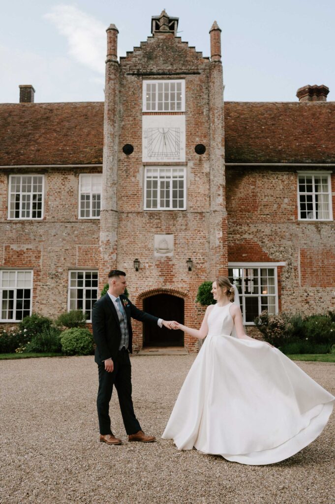 Bride and groom standing together in front of Bruisyard Hall during portraits