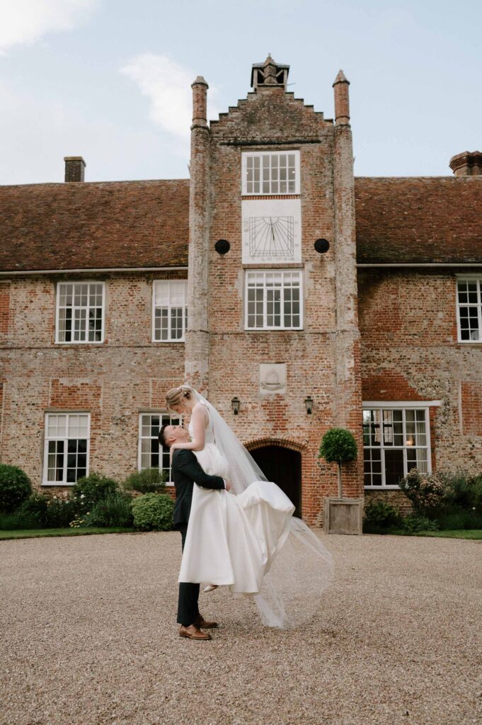 Bride and groom standing facing each other outside Bruisyard Hall during portraits