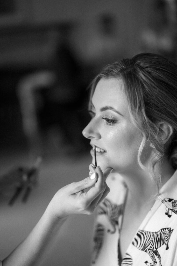 Black and white close-up of bride Heidi having her makeup applied during prep