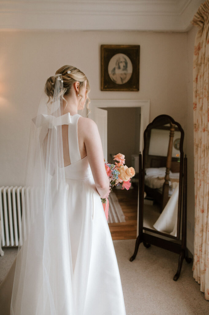 Bride seen from behind in her wedding dress during bridal prep at Bruisyard Hall