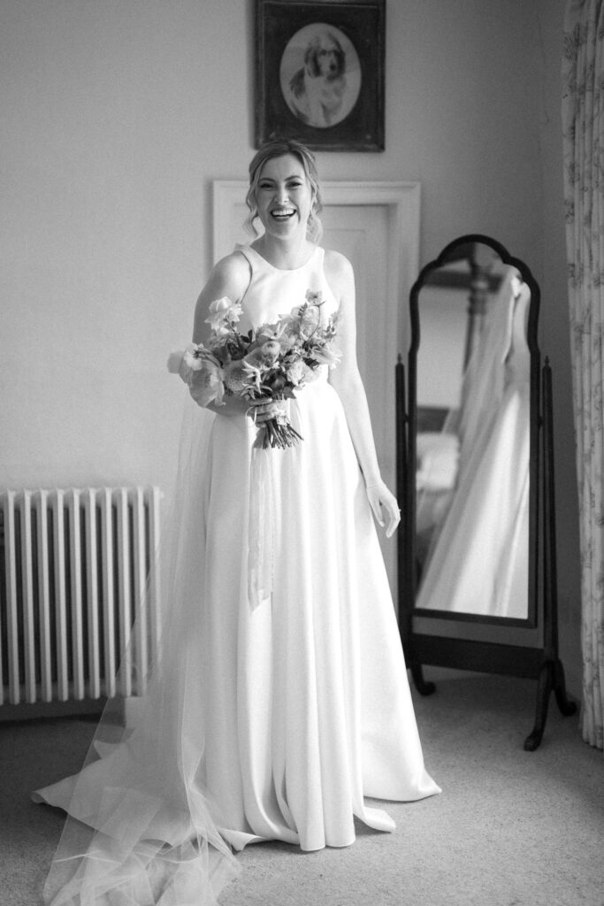 Black and white portrait of bride Heidi holding her bouquet and looking in the mirror during bridal prep