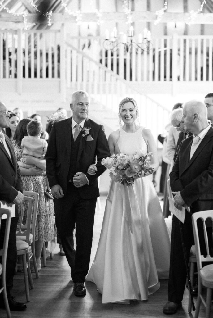 Bride walking down the aisle with her father during the ceremony at Bruisyard Hall