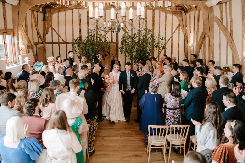 Bride and groom walking back down the aisle after the ceremony at Bruisyard Hall