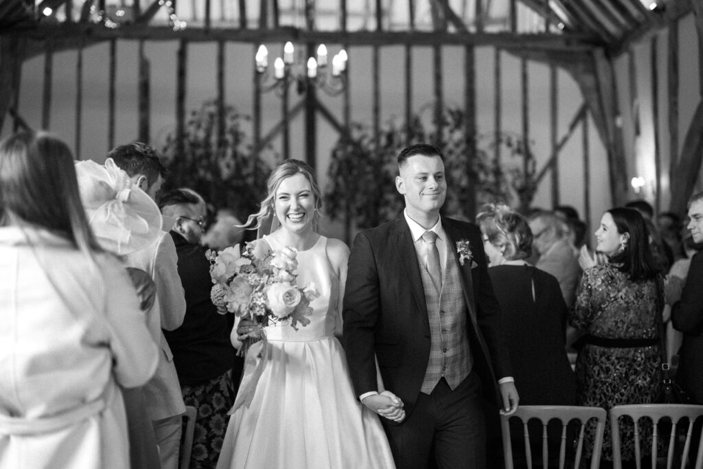 Bride and groom walking back down the aisle after the ceremony at Bruisyard Hall