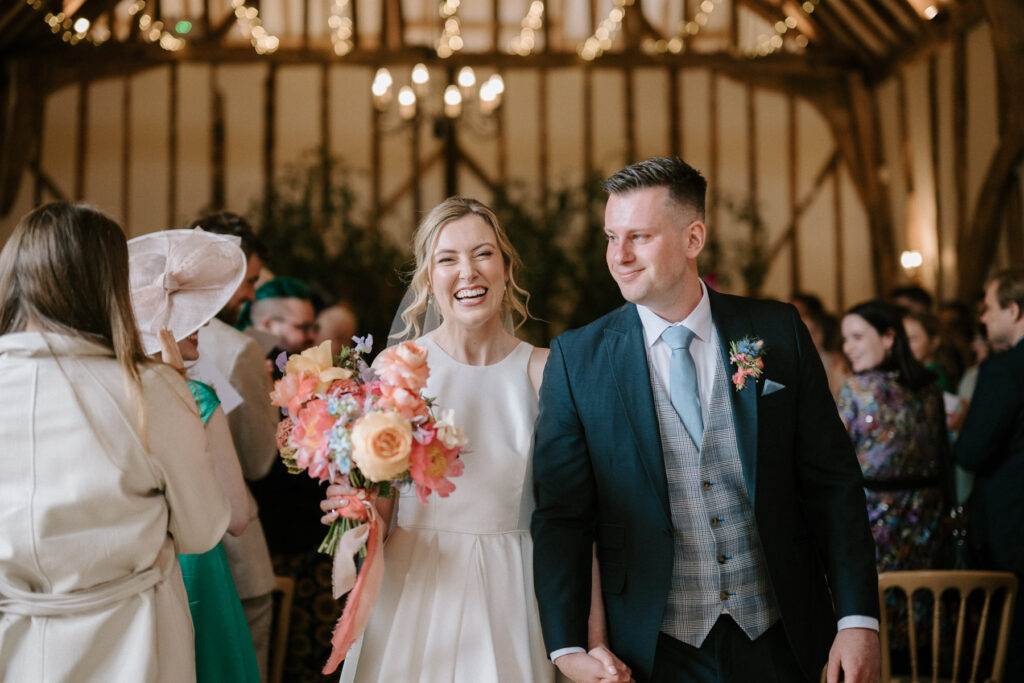 Bride and groom walking back down the aisle after the ceremony at Bruisyard Hall