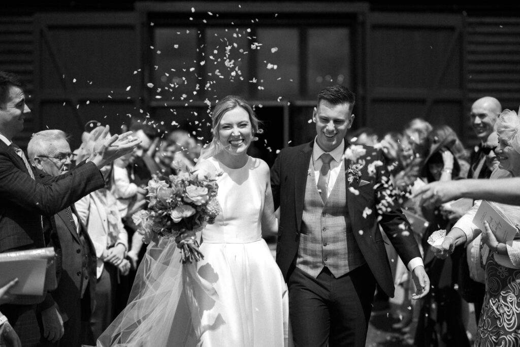Bride and groom walking through confetti outside Bruisyard Hall