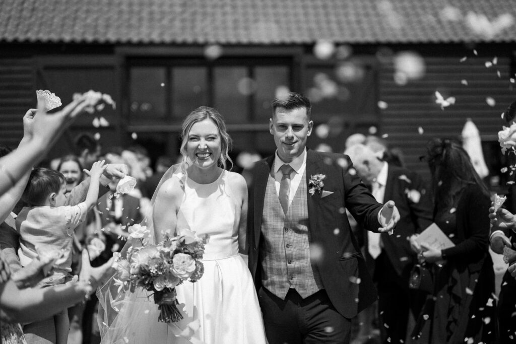 Bride and Groom walking  through confetti tunnel after their ceremony at Bruisyard Hall