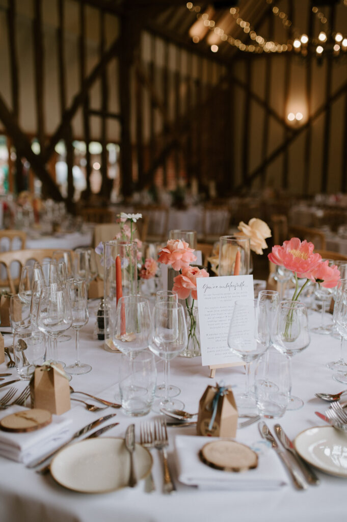 Wedding breakfast table set with brightly coloured flowers and place settings inside Bruisyard Hall