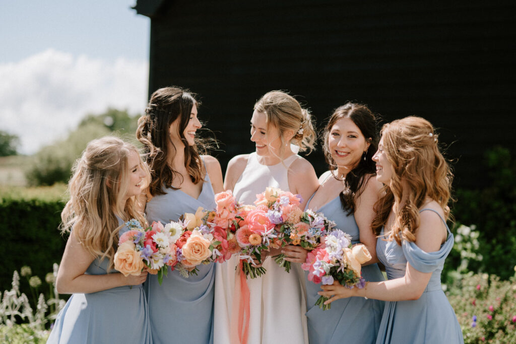 Bride surrounded by her bridesmaids holding bouquets at Bruisyard Hall