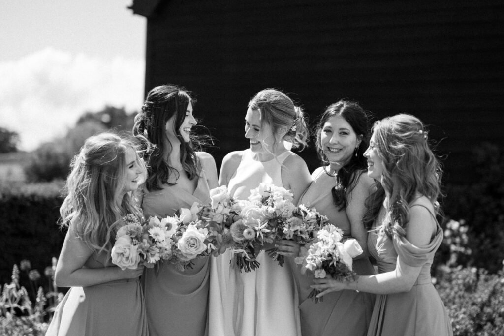 Bride and her bridesmaids standing together and smiling at Bruisyard Hall