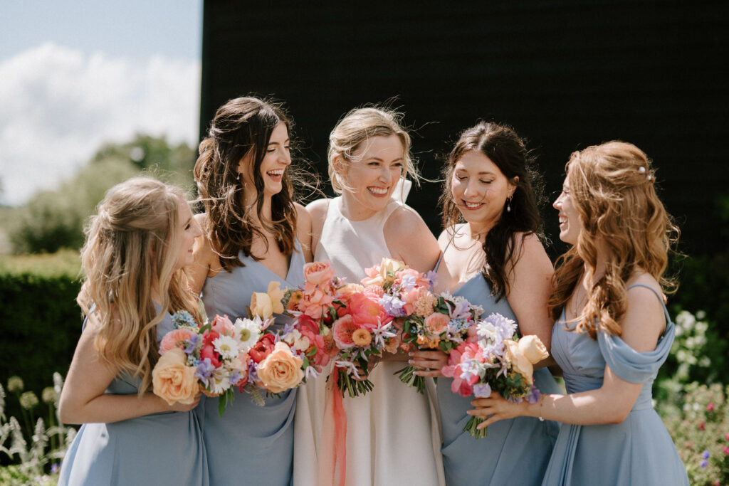 Bride and her bridesmaids standing together and smiling at Bruisyard Hall