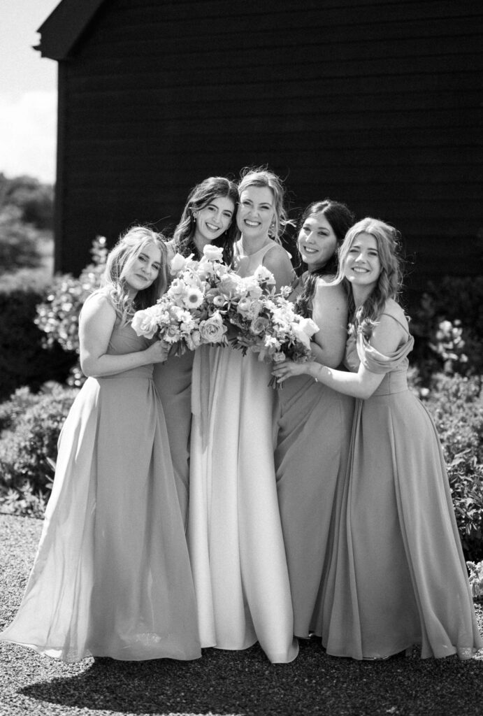 Bride standing with her bridesmaids holding bouquets outside at Bruisyard Hall