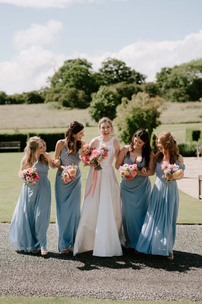 Bride and her bridesmaids standing together holding bouquets at Bruisyard Hall