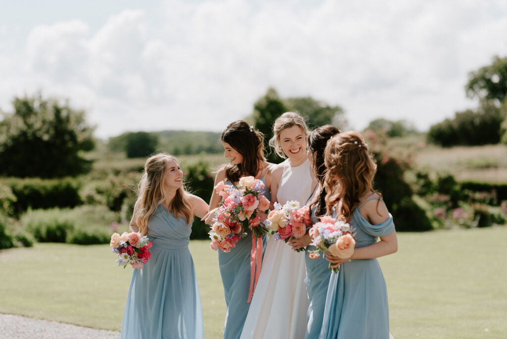 Bride walking with her bridesmaids holding bouquets at Bruisyard Hall