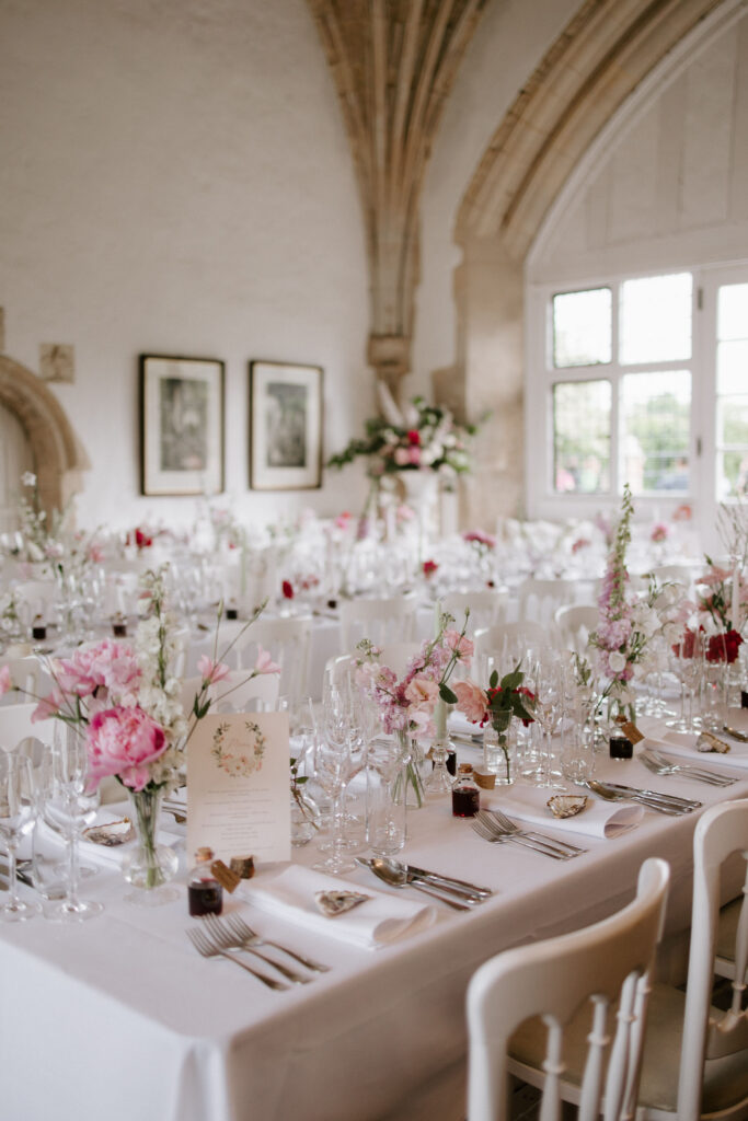 Wedding reception setup inside Butley Priory featuring stone arches and a fireplace.