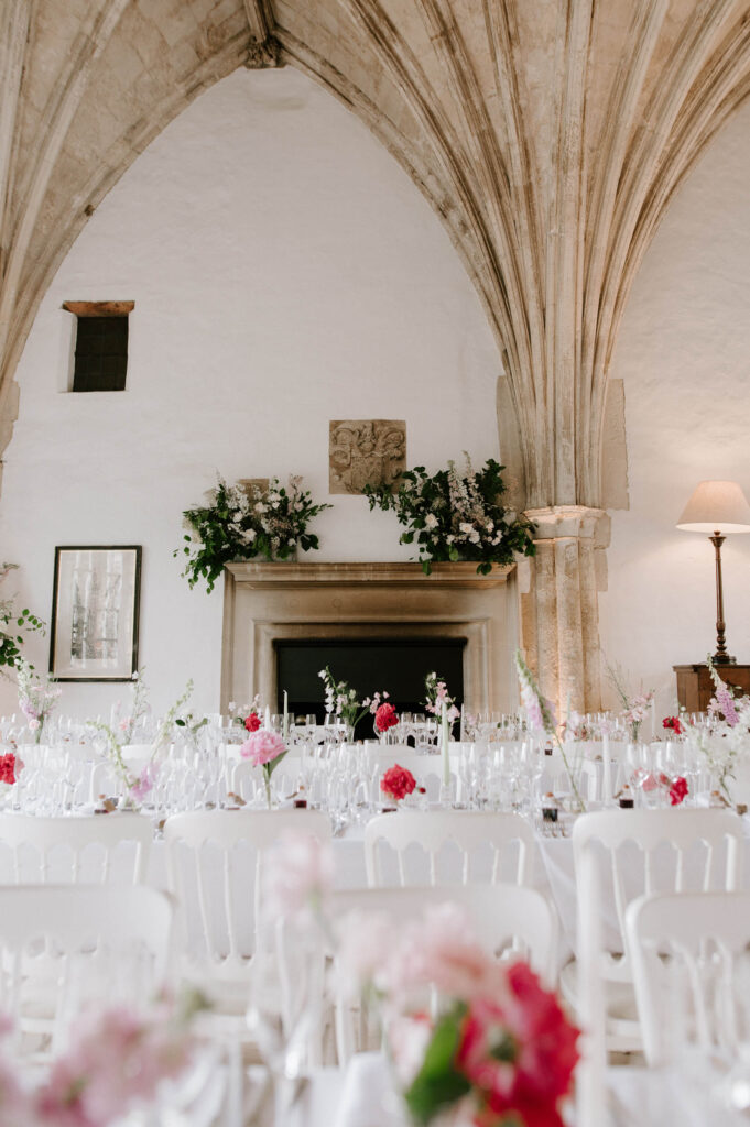 Stone vaulted arches and floral arrangements decorating the wedding reception at Butley Priory.