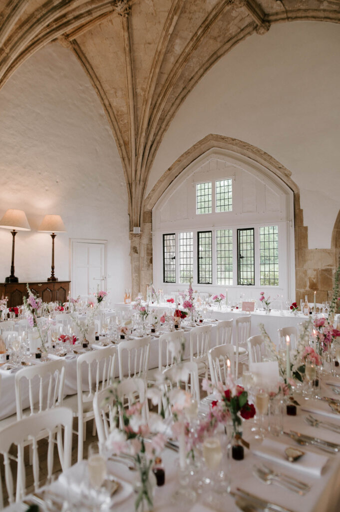 Romantic pink and white wedding table details with candles inside Great Hall at Butley Priory