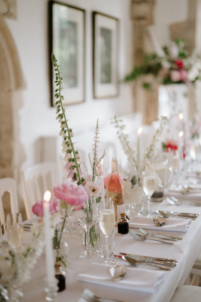 Romantic pink and white wedding table details with candles inside Great Hall at Butley Priory