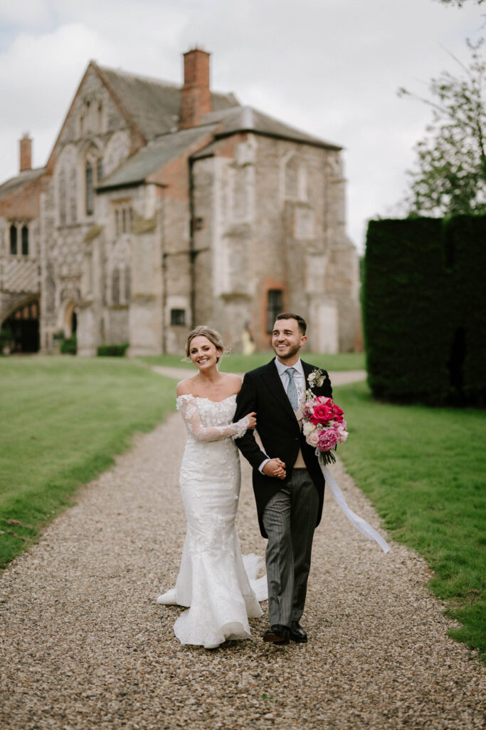 bride and groom walking down butley priory drive