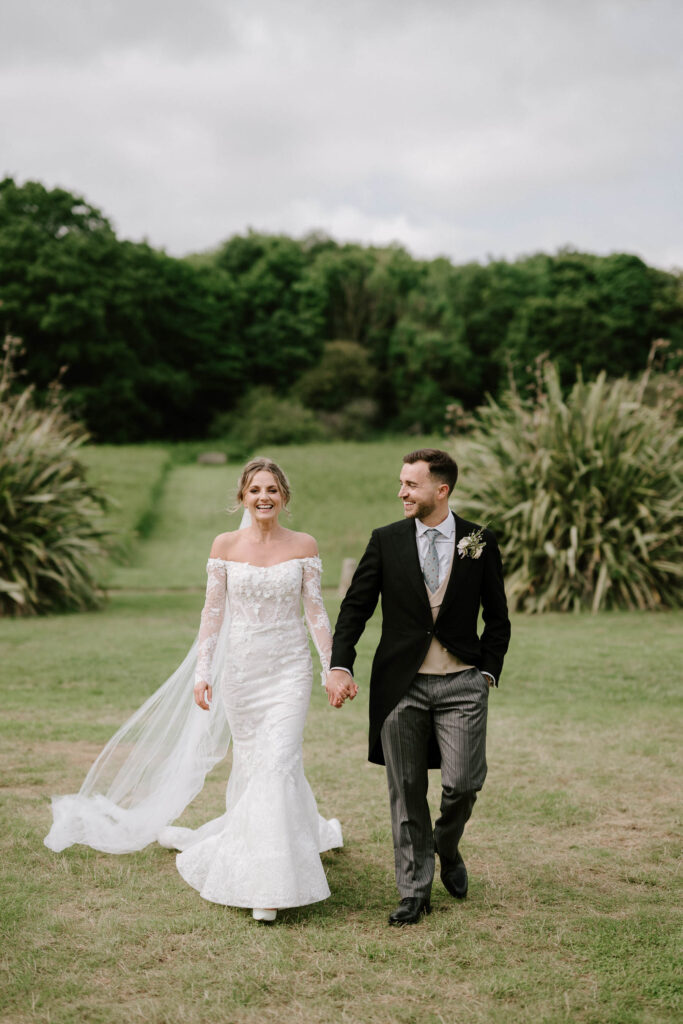 Bride and groom walking hand in hand through the grounds at Butley Priory.