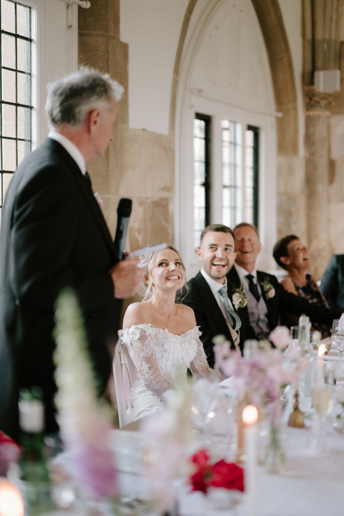 Father of the bride giving a speech as the couple listen during the wedding reception.