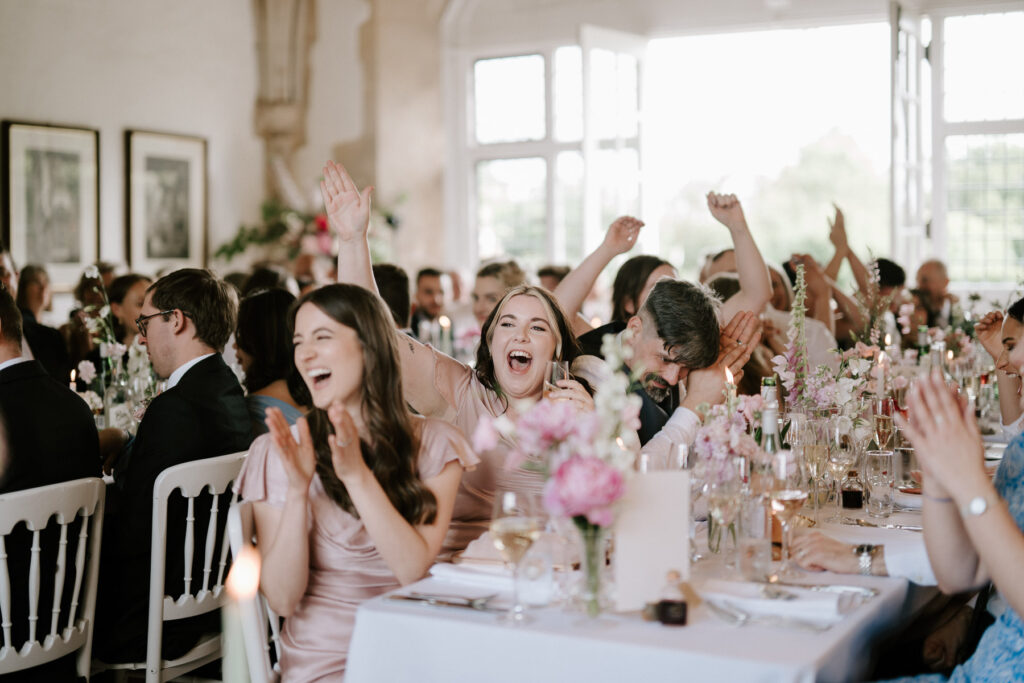 Wedding guests cheering and celebrating during speeches at Butley Priory