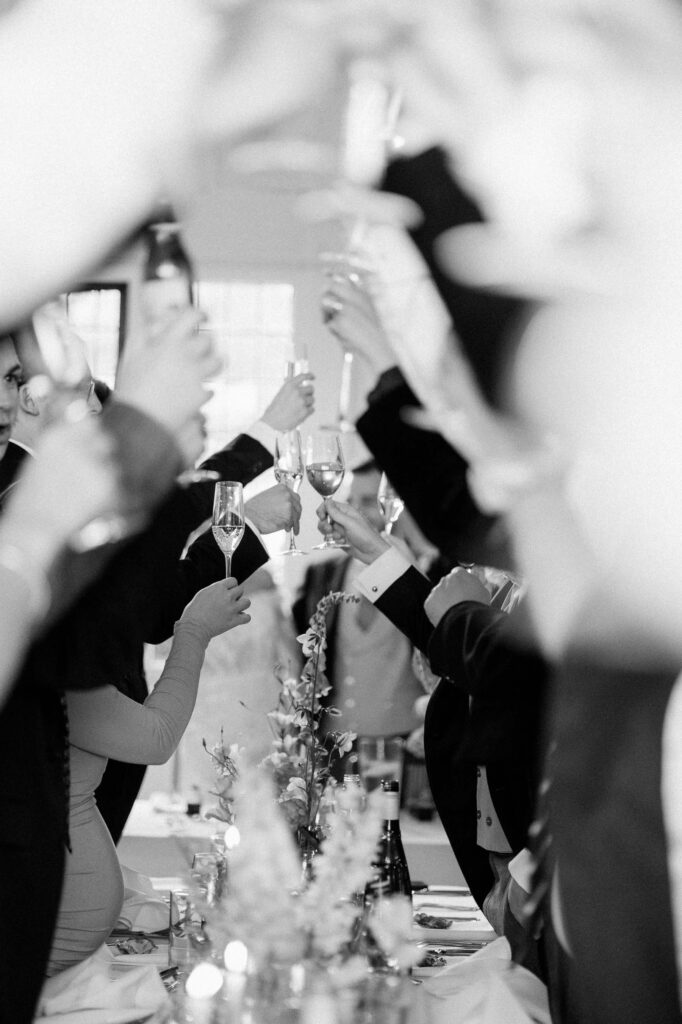 Wedding guests raising glasses in celebration during speeches.