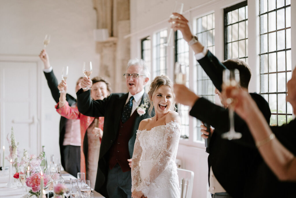 Bride and groom cheering and raising glasses during wedding speeches.