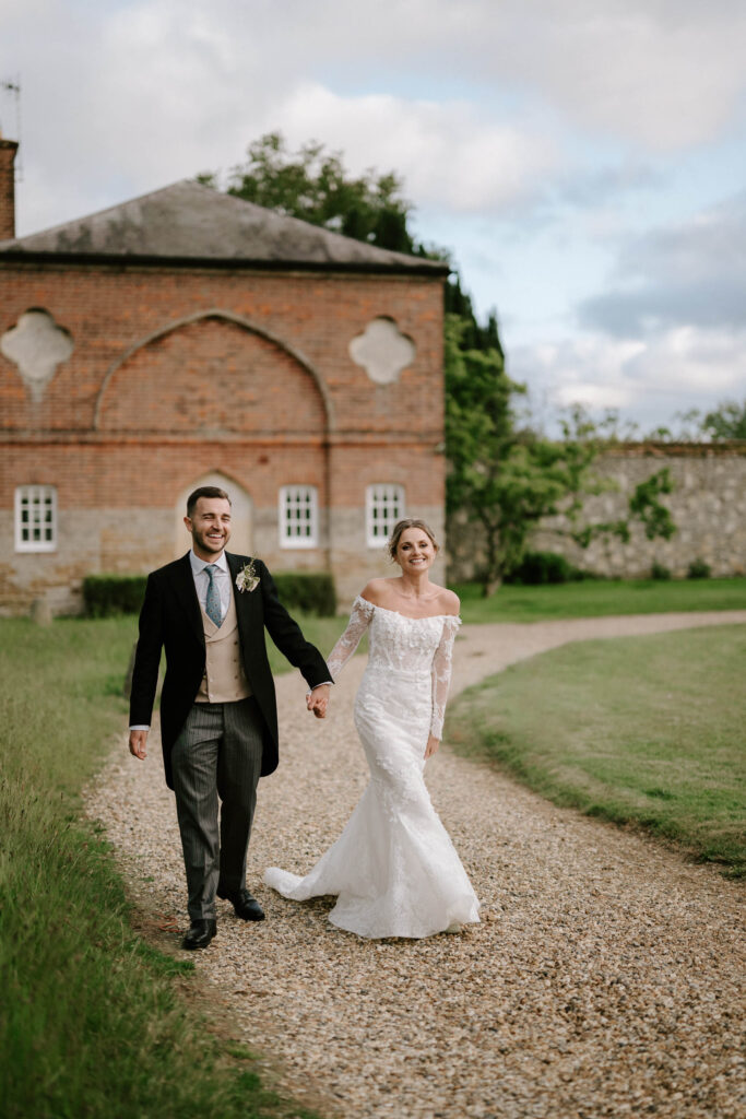 Bride and groom walking along the path at Butley Priory.