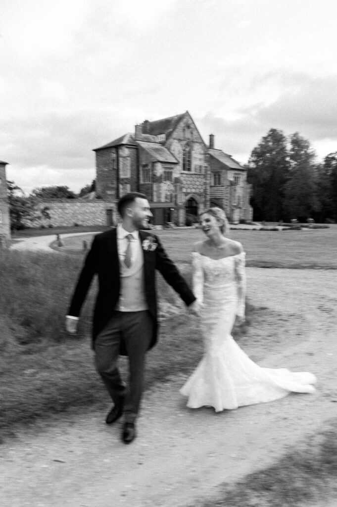 Bride and groom walking hand in hand through the grounds of Butley Priory.