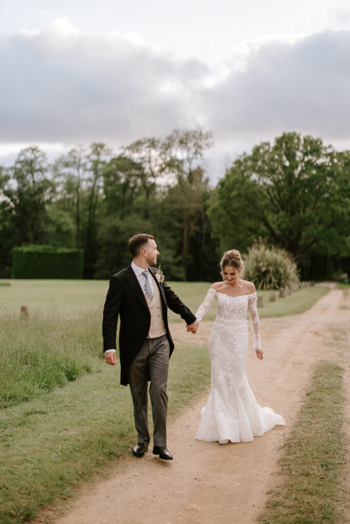 Bride and groom holding hands while walking through the Suffolk countryside.