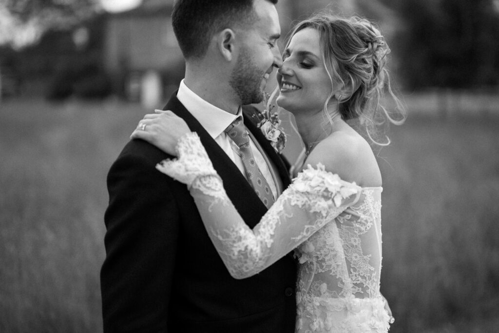 Bride and groom standing close together and smiling during couple portraits.