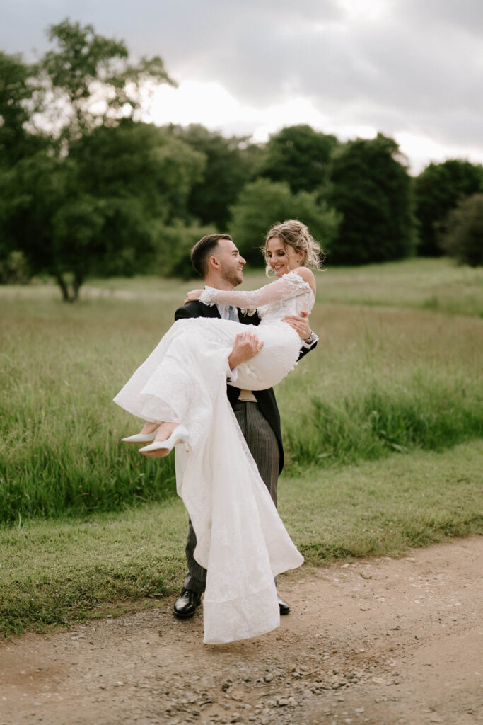 Groom lifting the bride in a field during relaxed wedding portraits.