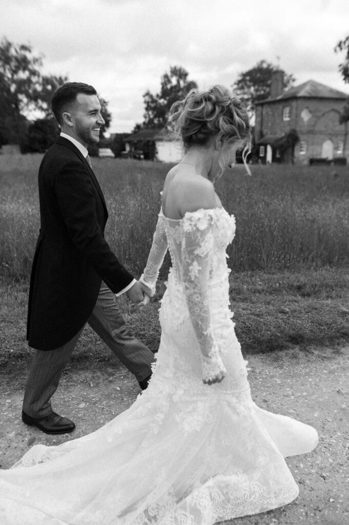 Bride and groom walking hand in hand during portraits at Butley Priory.