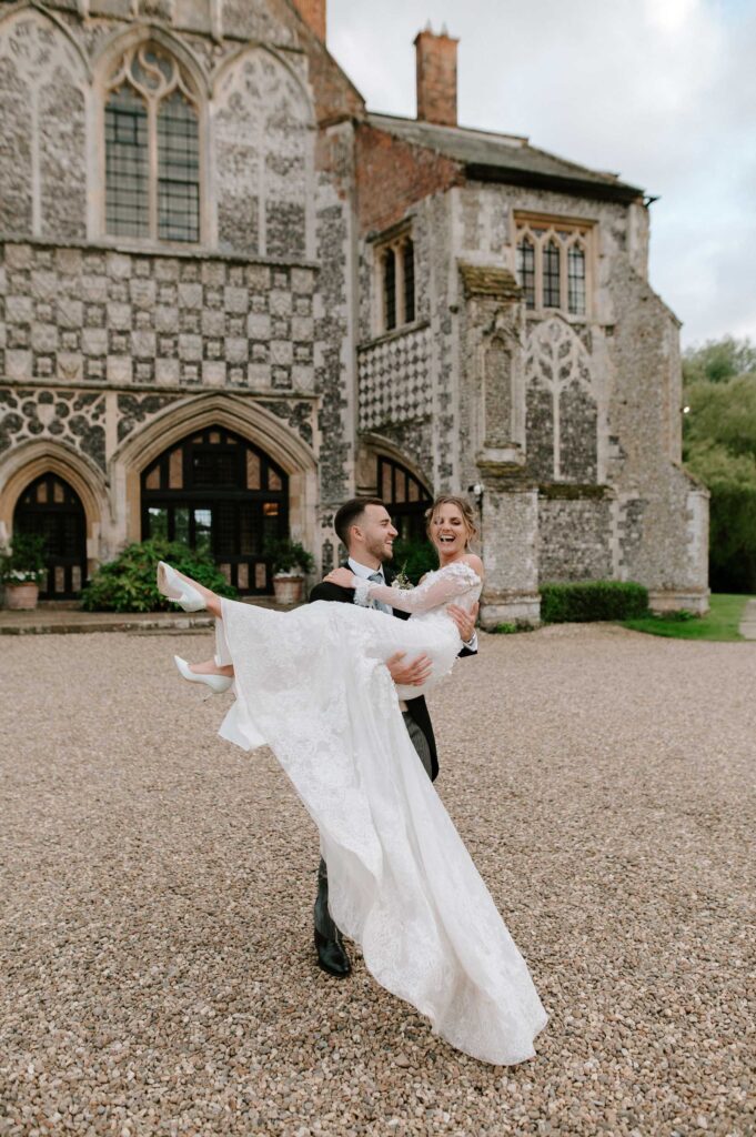 Bride and groom spinning together in front of Butley Priory.